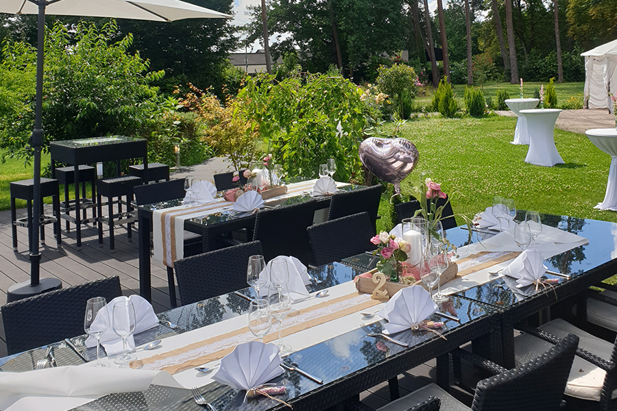 Ein Esstisch-Set im Freien für eine feierliche Privat- oder Firmenfeier, elegant gedeckt mit gefalteten Servietten, Gläsern und Blumengestecken – perfekt für Ihre nächste unvergessliche Veranstaltung an unserem einzigartigen Veranstaltungsort.